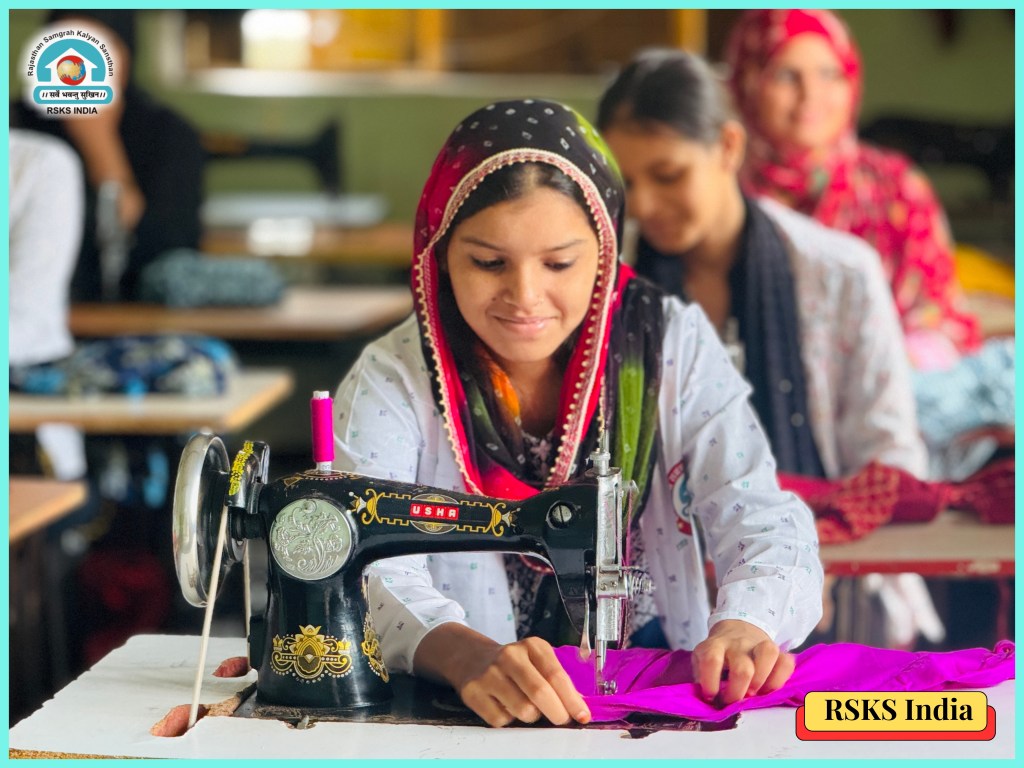 A young woman sewing a bright pink fabric on a sewing machine, with other women in the background, in an educational setting related to textile skills.