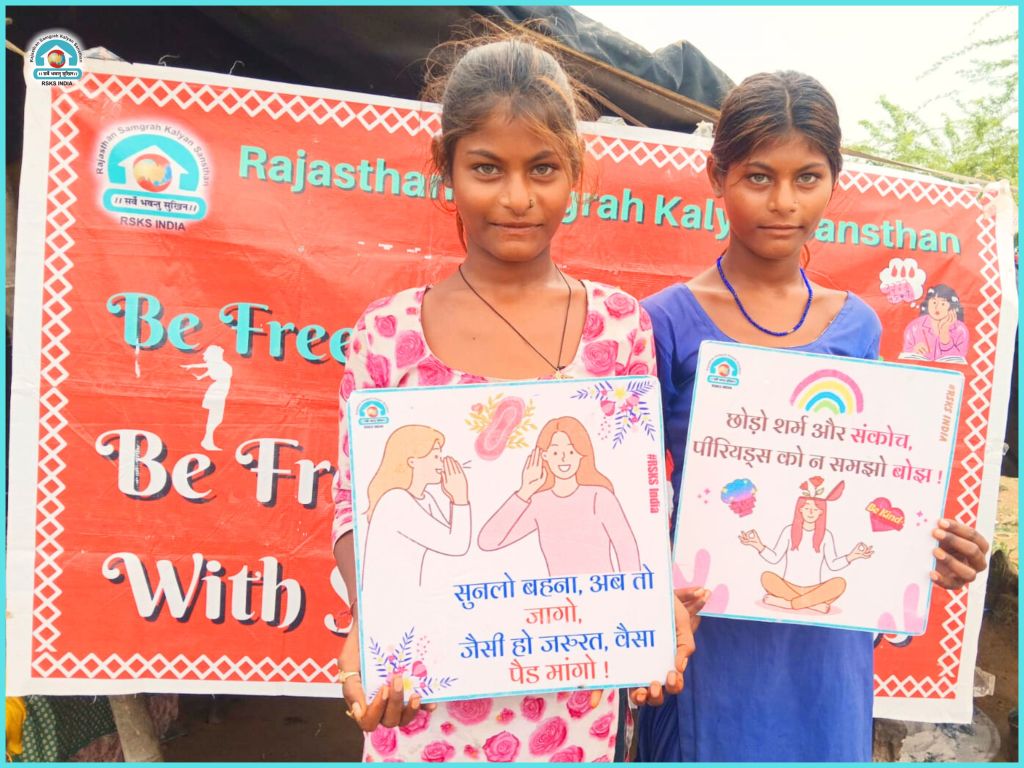 Two young girls holding colorful awareness posters in front of a banner that promotes freedom and self-acceptance.
