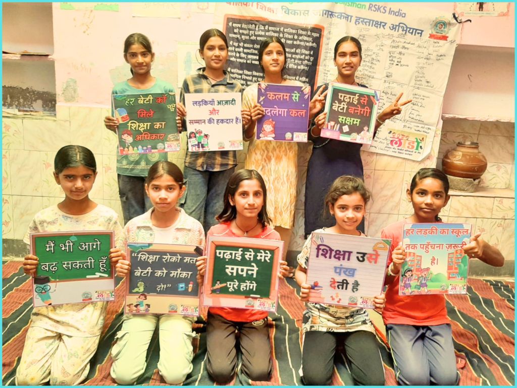 A group of young girls holding colorful placards promoting education and women's rights, standing together in a classroom setting.